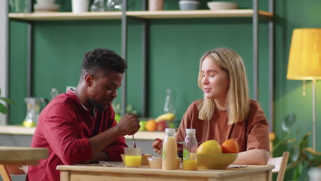 Young-Multiethnic-Couple-Eating-Healthy-Food-and-Chatting-at-Home